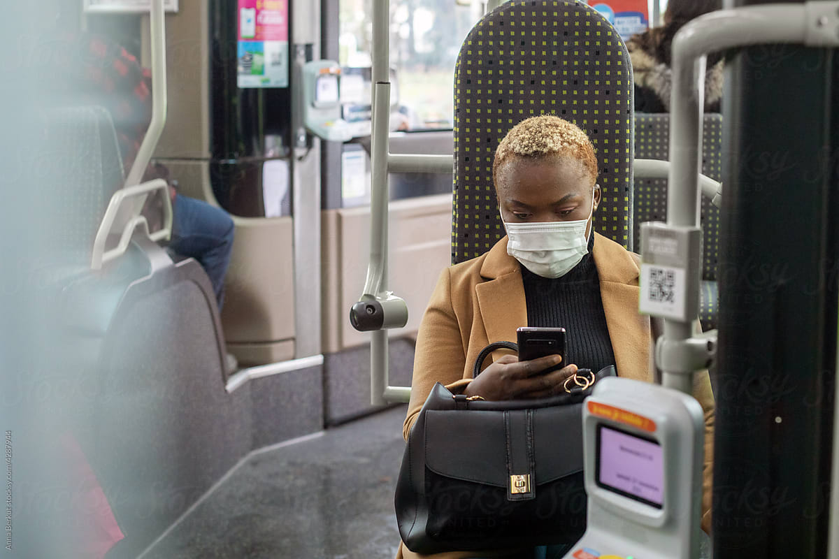 woman with mobile phone in the bus, wearing face mask