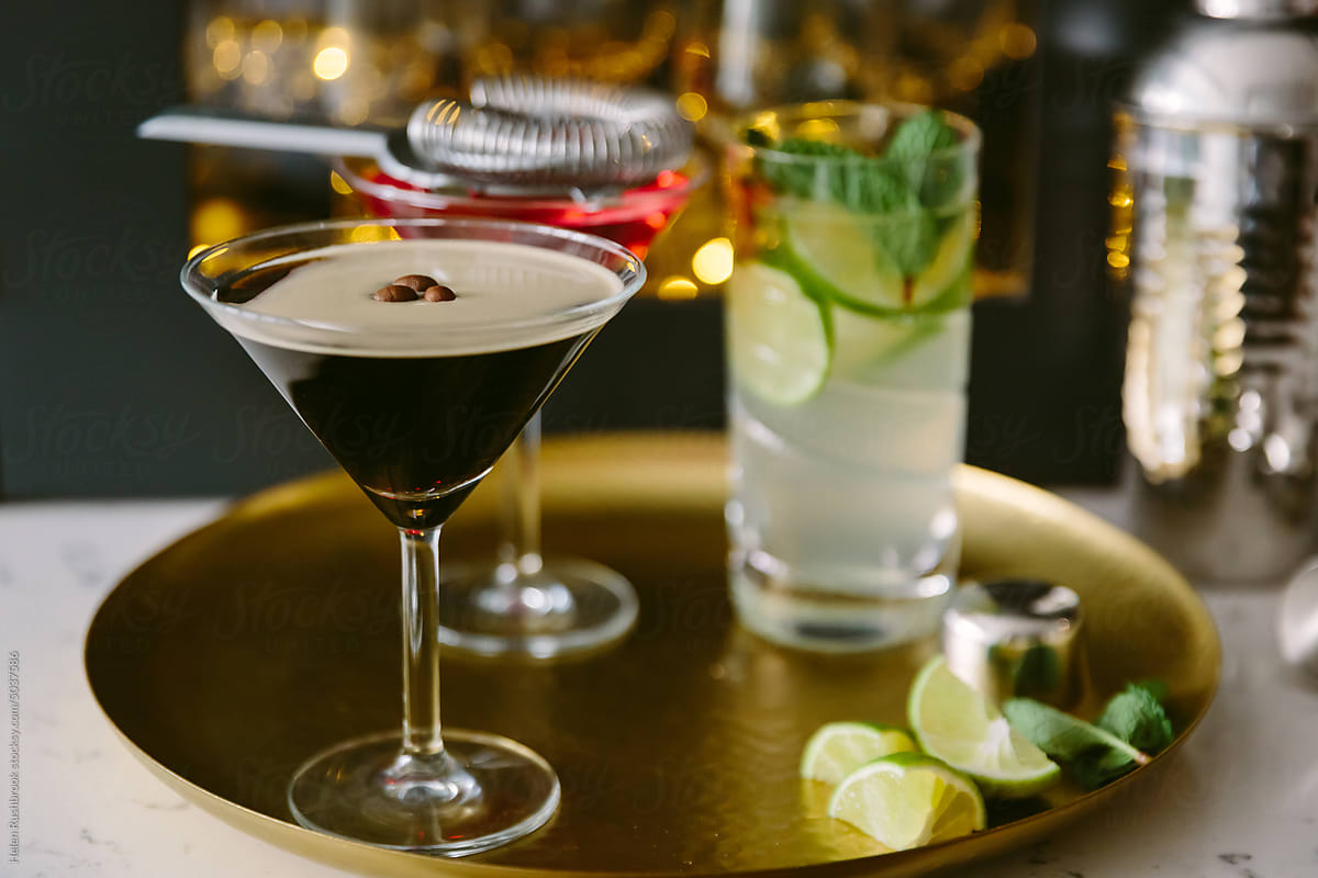 An espresso Martini on a brass tray with other mixed drinks.