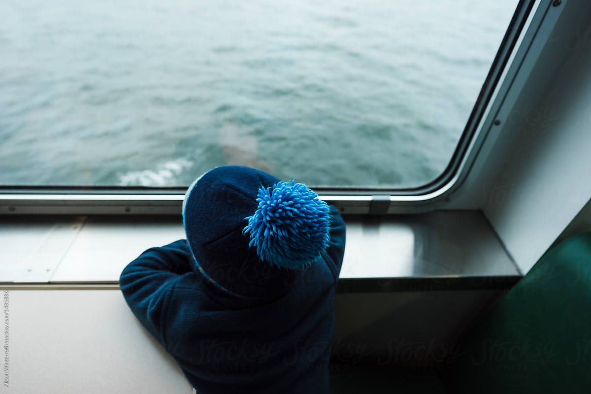 A Boy Looks Out The Window Of A Ferry