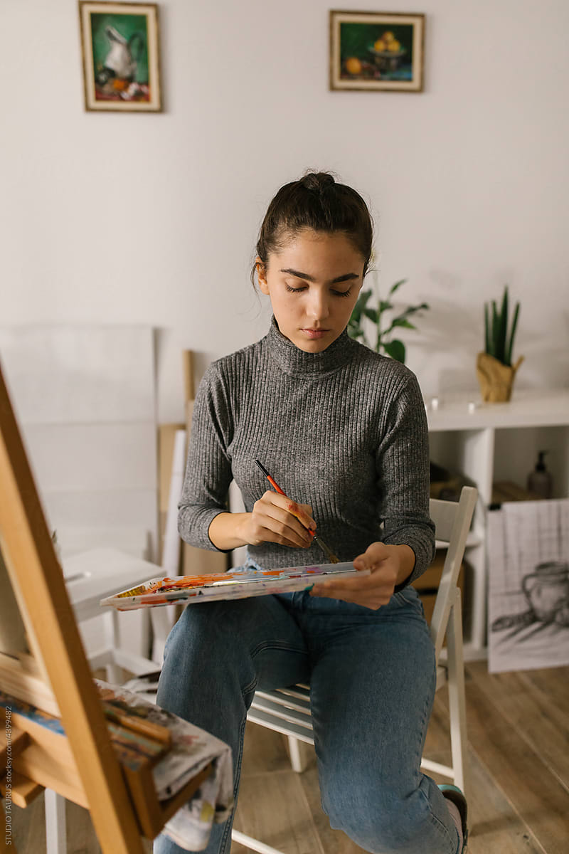 Art student sitting and painting at home