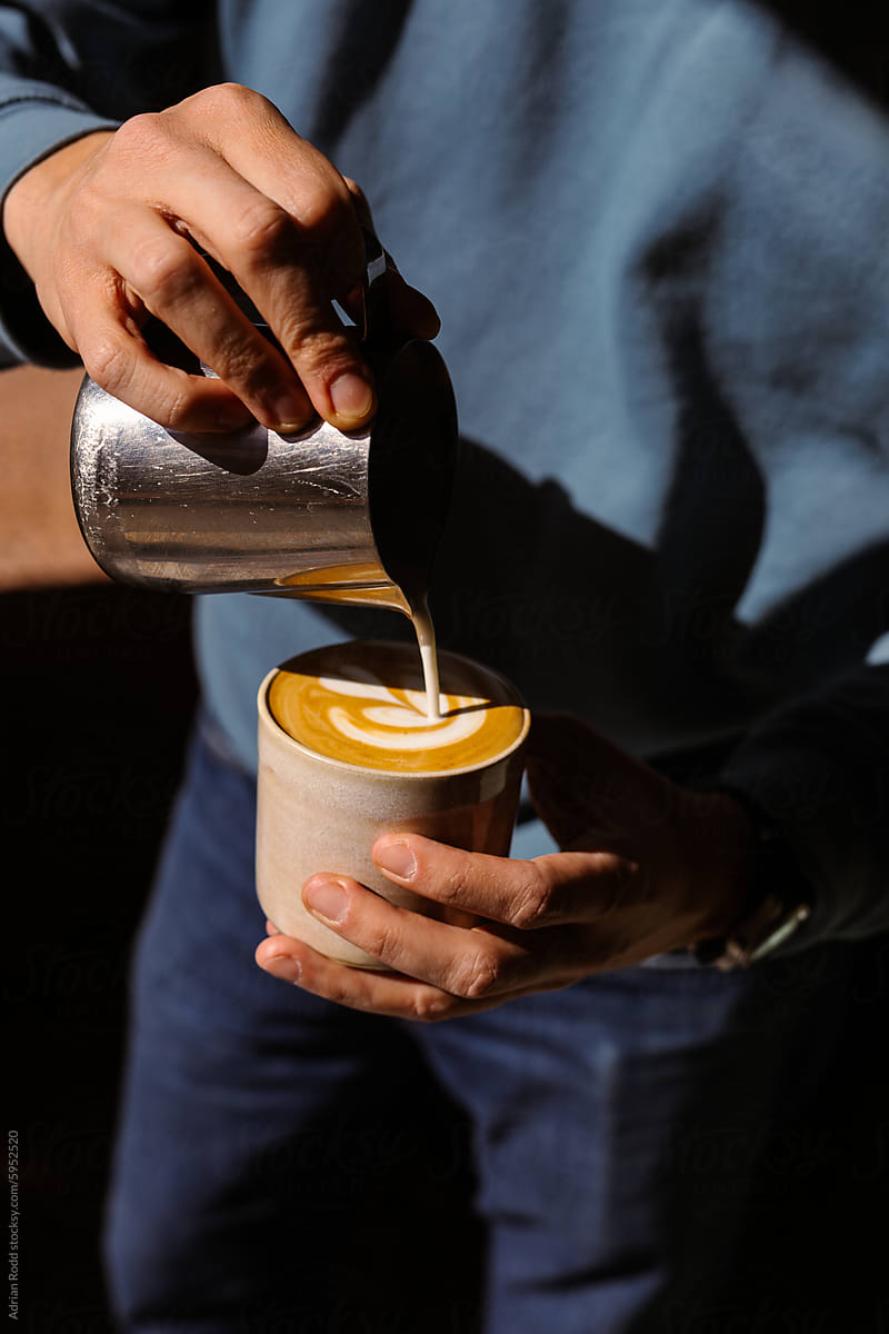 Barista decorating a specialty coffee with latte art