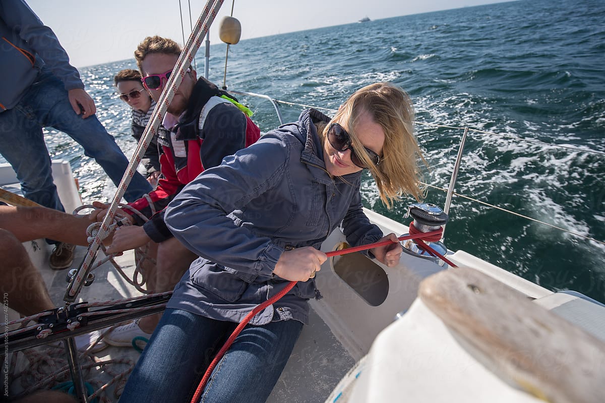 Woman and crew on sail boat working together on rigging for ocean adventure