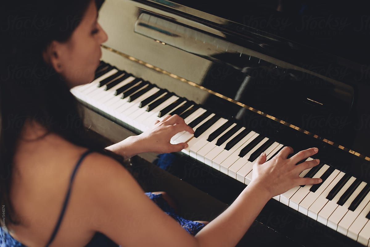 Beautiful girl in blue dress playing the piano