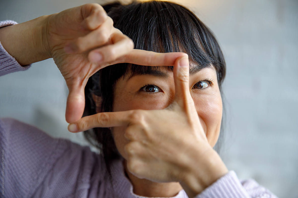 Closeup portrait of happy woman making finger frame at home
