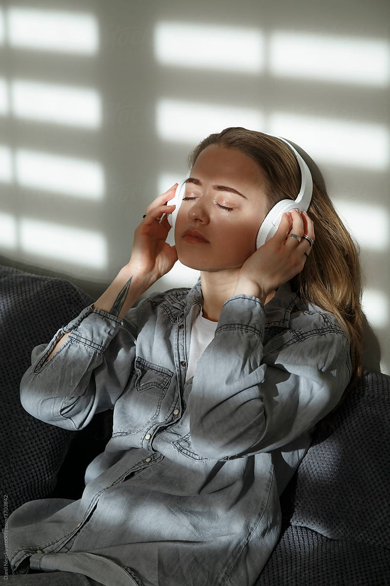 Content woman listening to songs in headphones at home