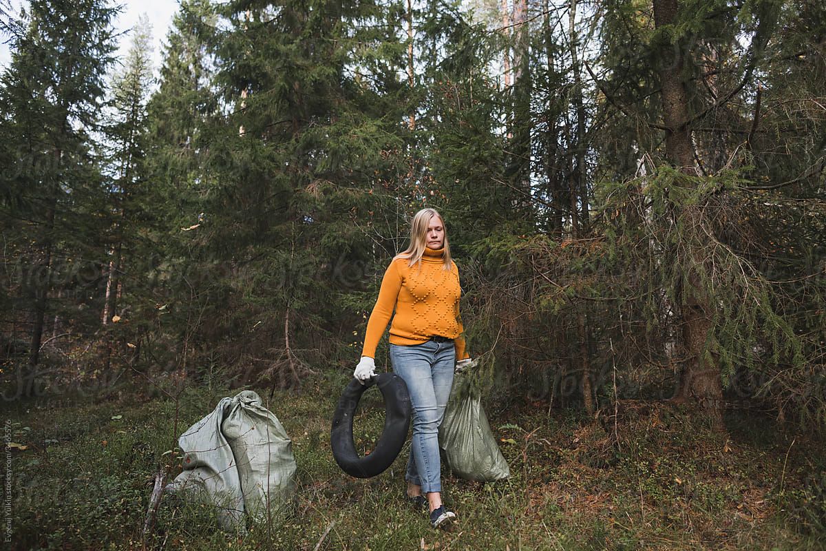 Woman collects plastic litter in the forest