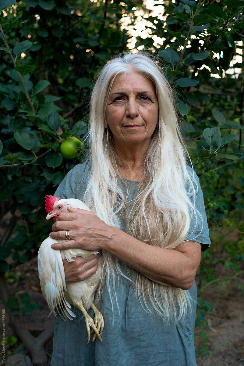 Mature woman standing in the countryside with chicken