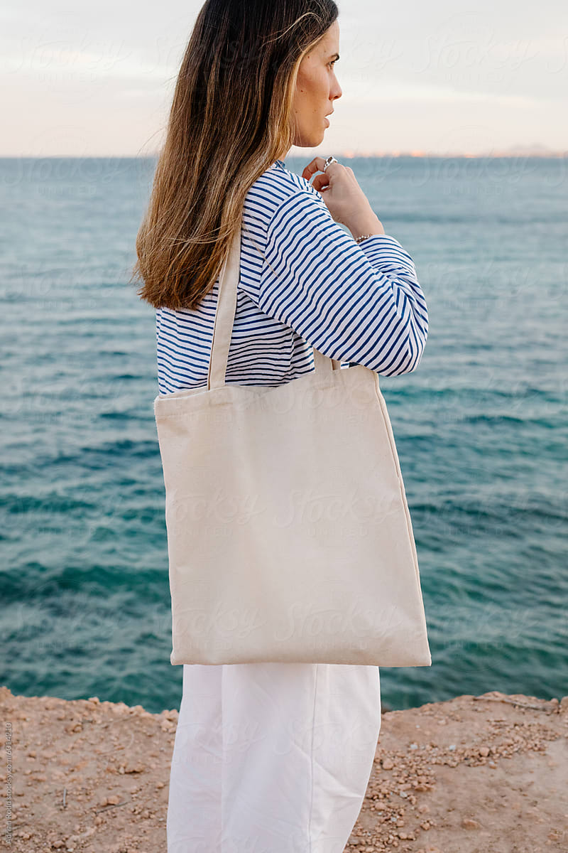 Portrait of a young woman posing holding a plain white tote bag