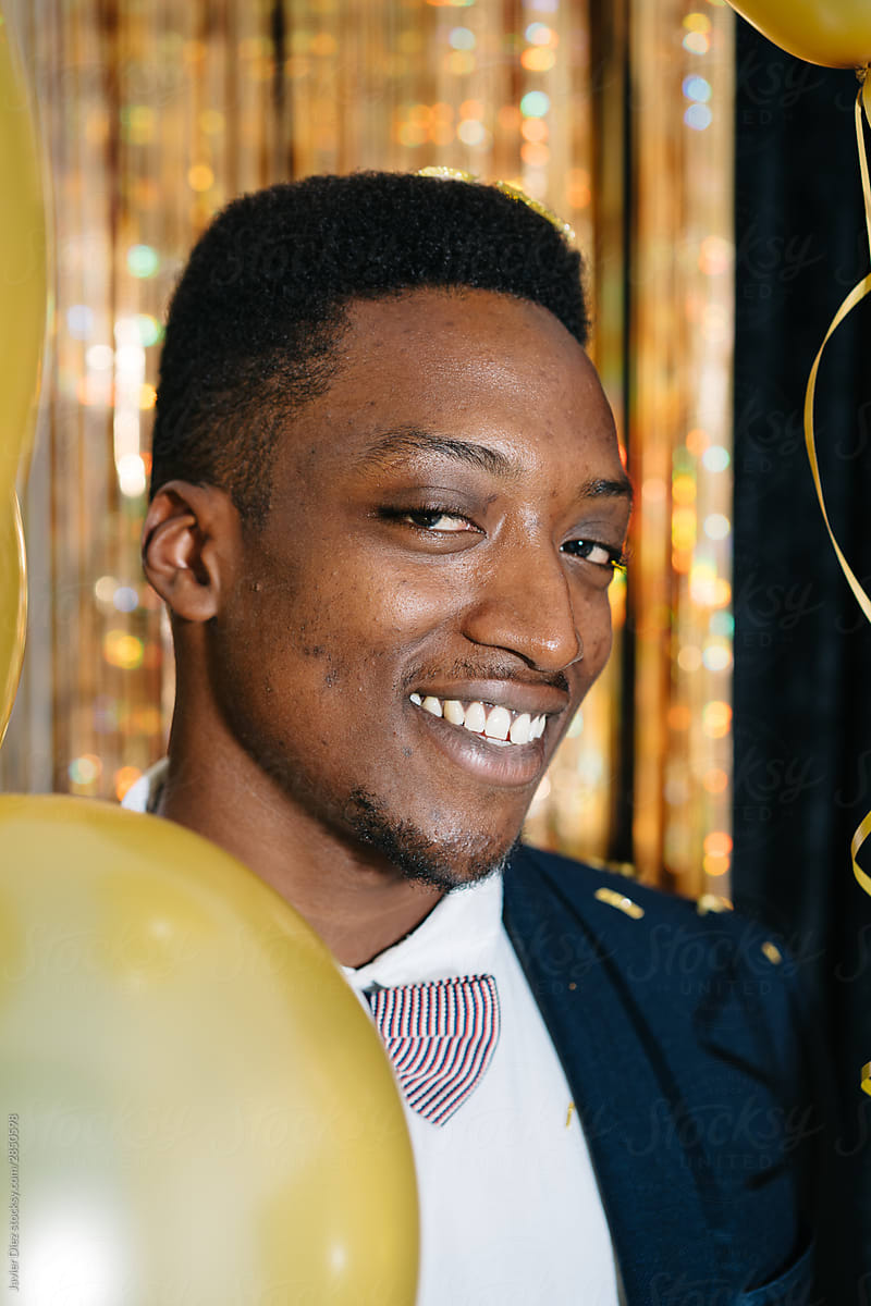 Joyful African American man with golden balloons looking at camera