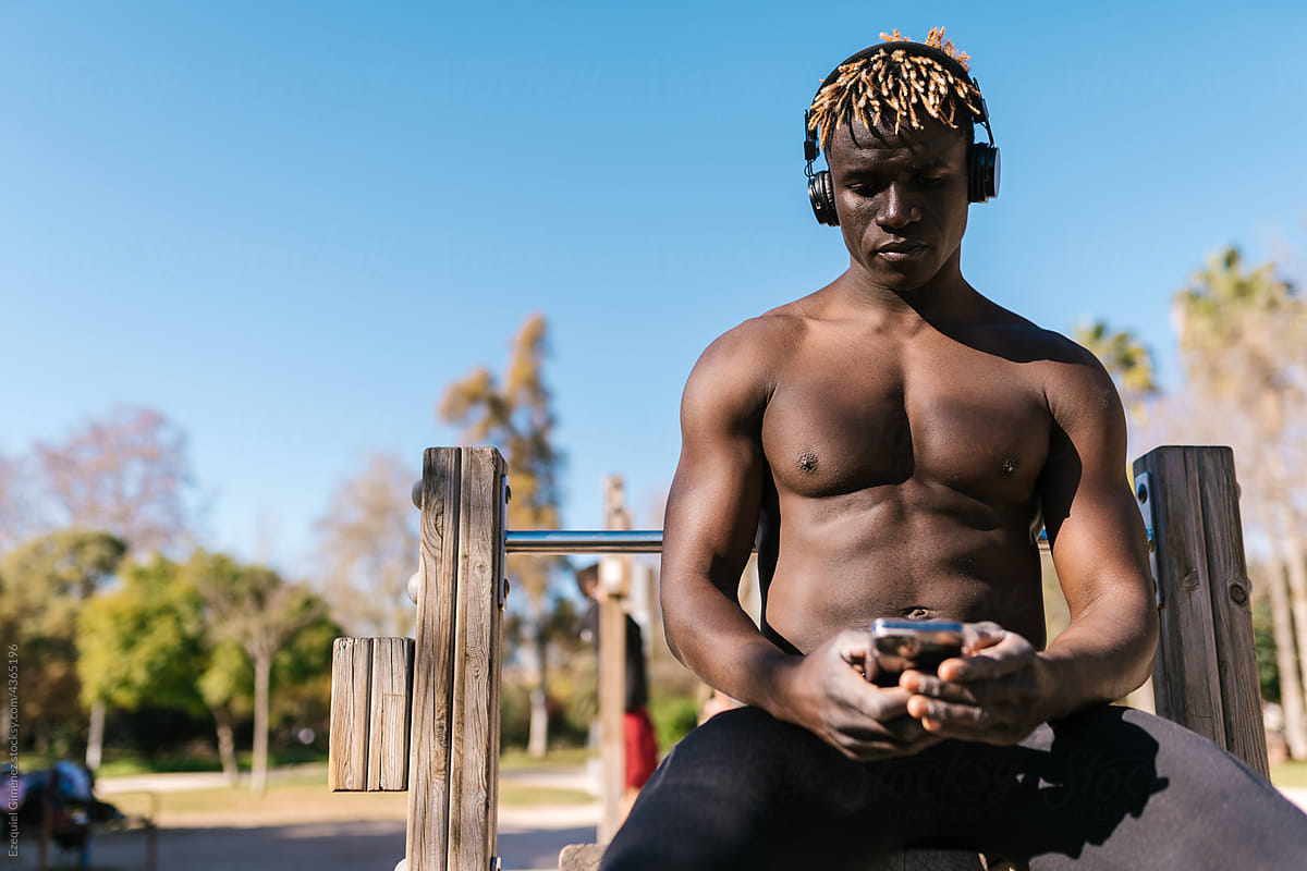 African sportsman with phone and headphones in park