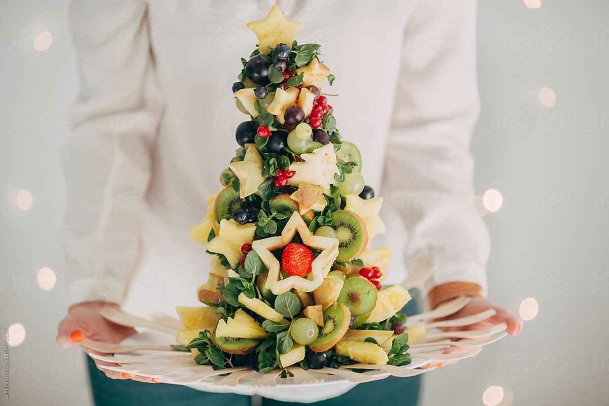Woman Holding a Christmas Tree Made of Fruit