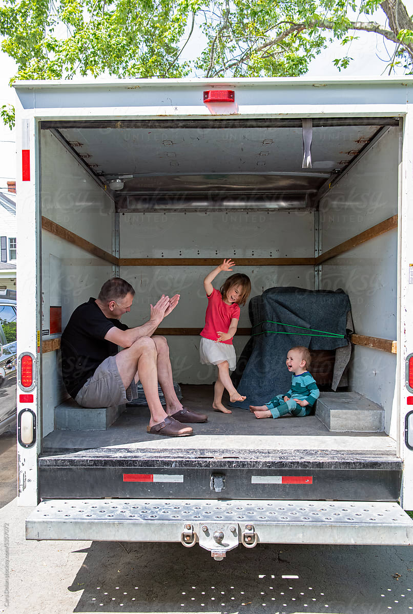 Child Happily Dances Inside Empty Moving Truck with her Family