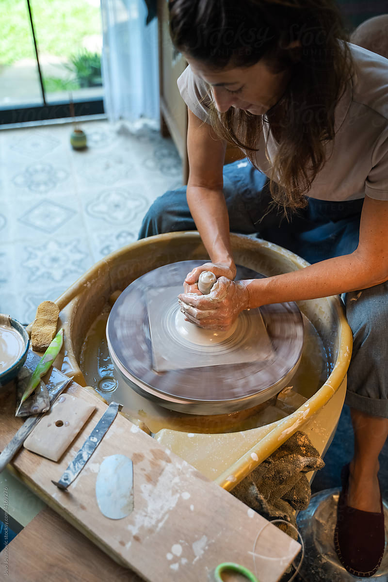 Woman sculpting clay on spinning wheel in art studio