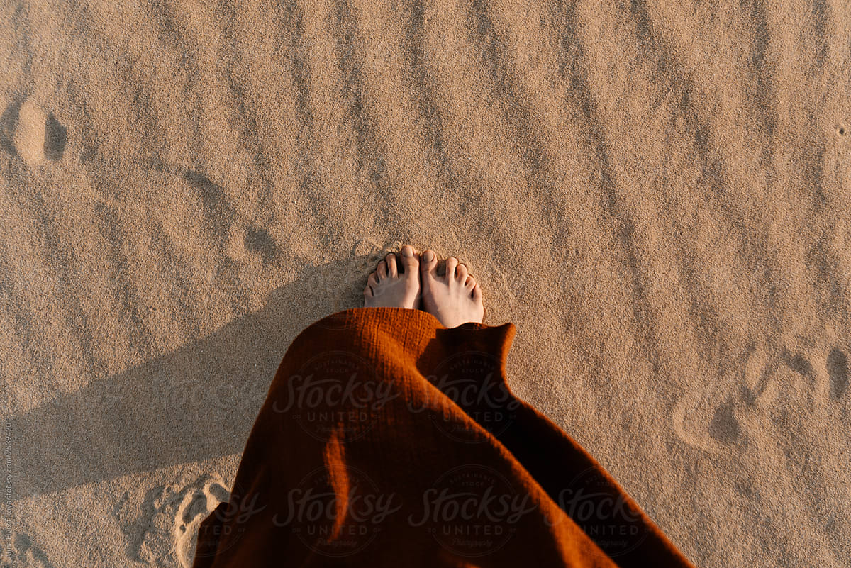 Woman’s feet standing on hot sand in desert.