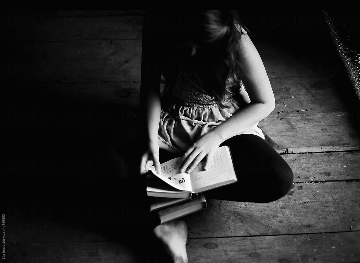 young woman sitting on dirty floor reading