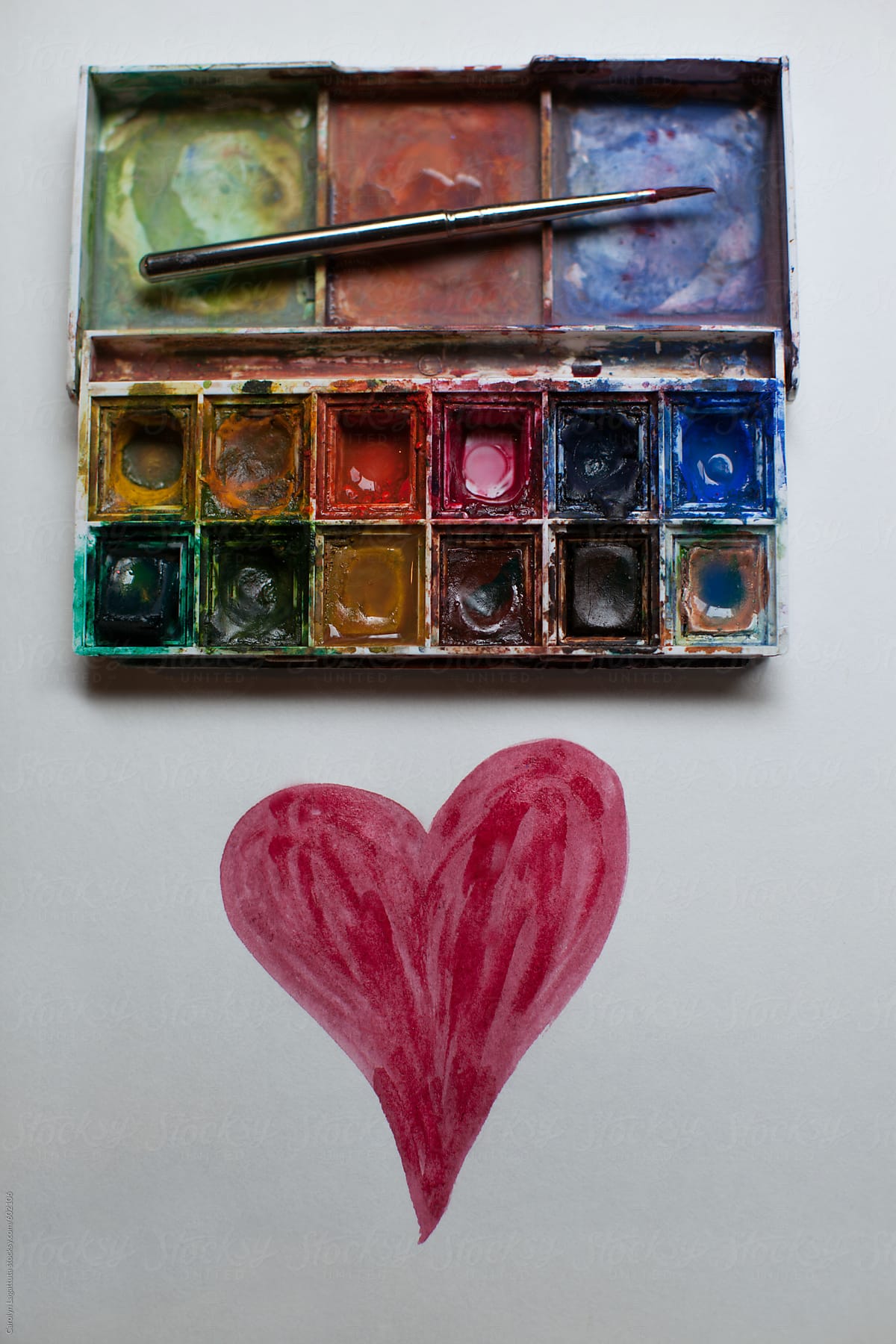 Well loved mini-pallette of paints with a red heart on paper