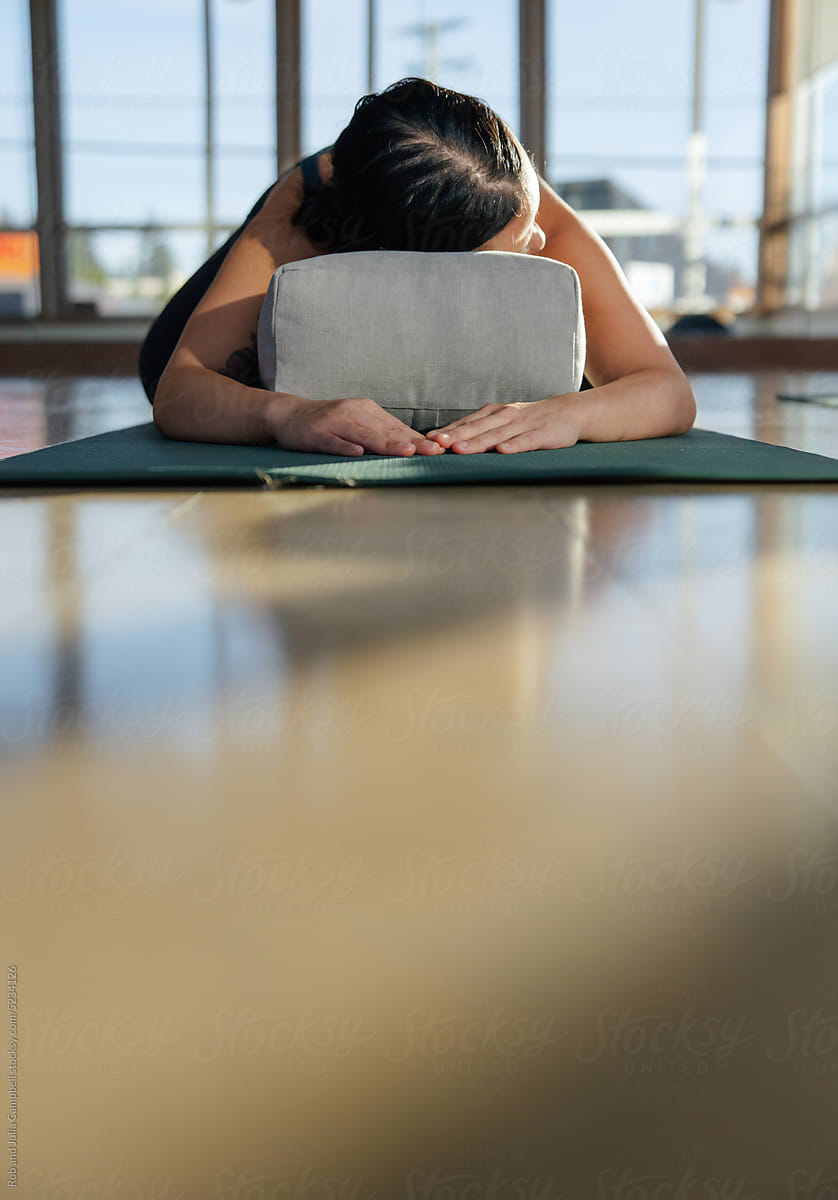 Woman in child's pose using yoga pillow.