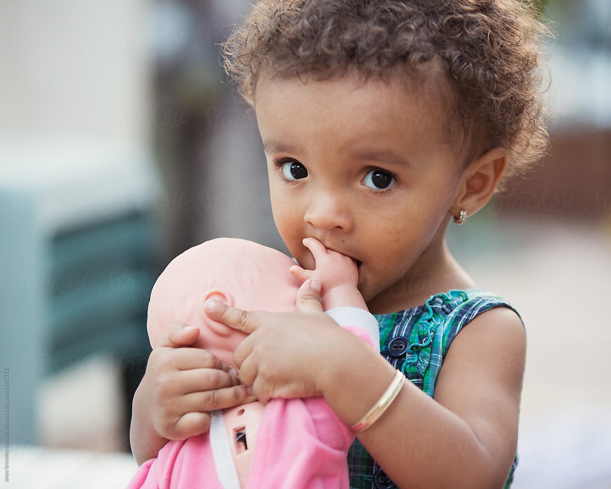 A pretty toddler girl holding her baby doll