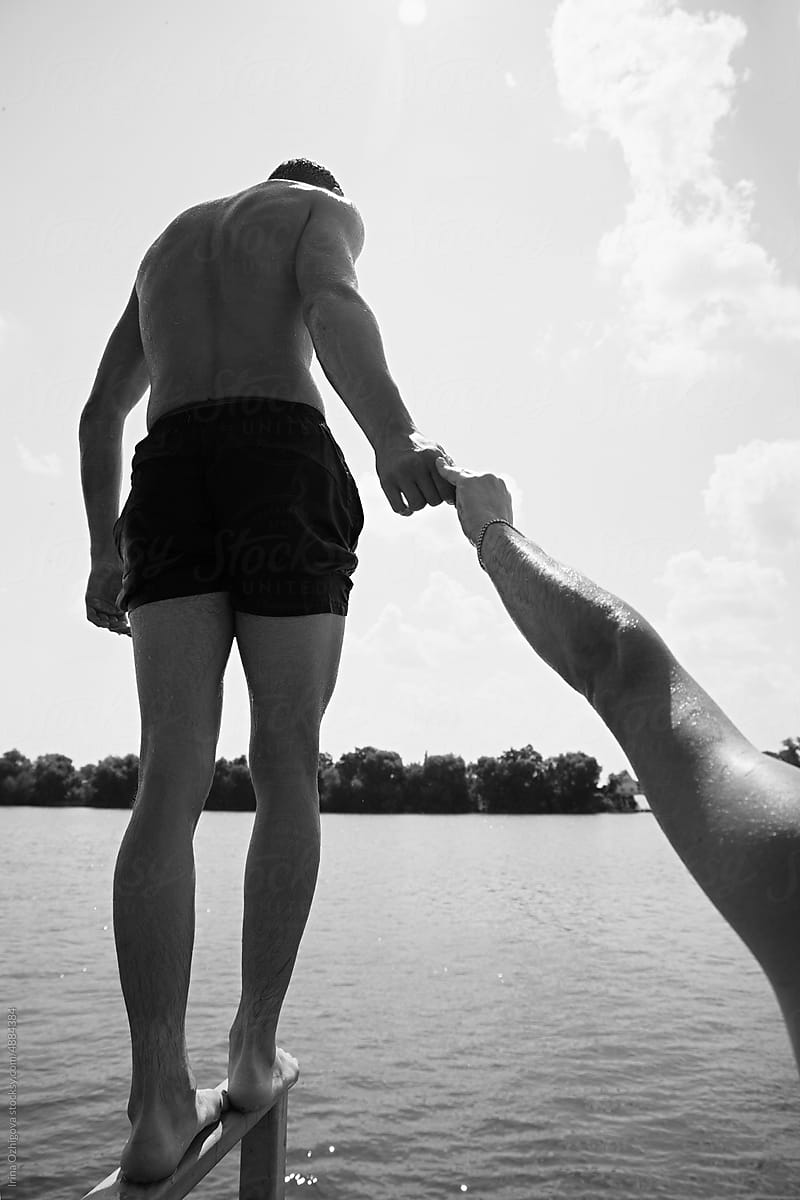 Anonymous man holding hand of friend near lake