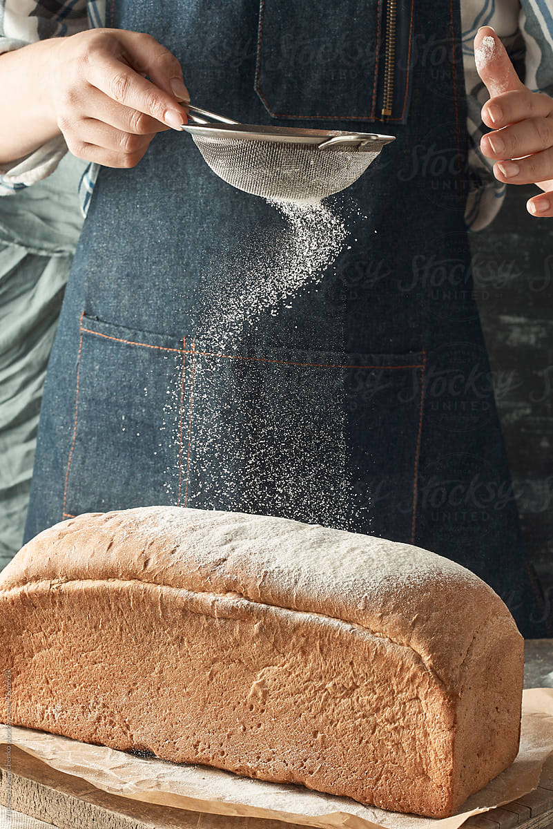 Fresh rustic bread on an old wooden board, a male baker in an ap