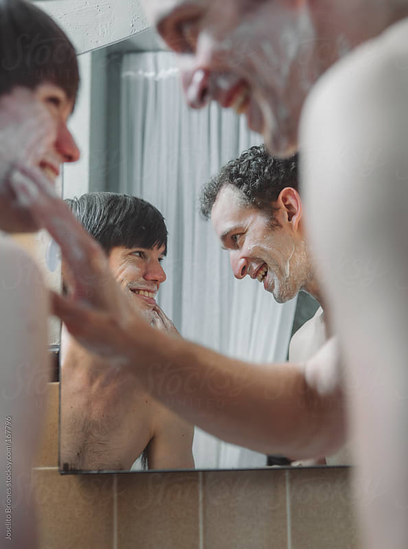 Gay couple shaving together, sharing a bathroom in the morning
