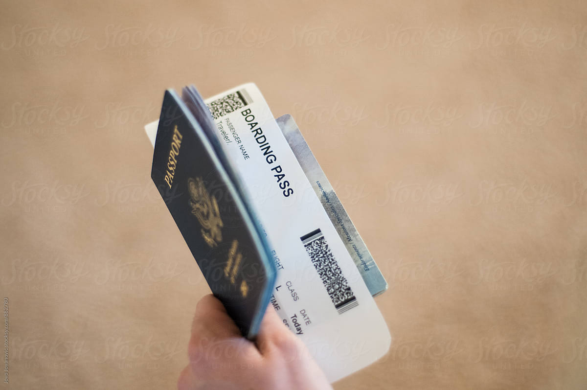 Closeup of hand holding passport with boarding pass in