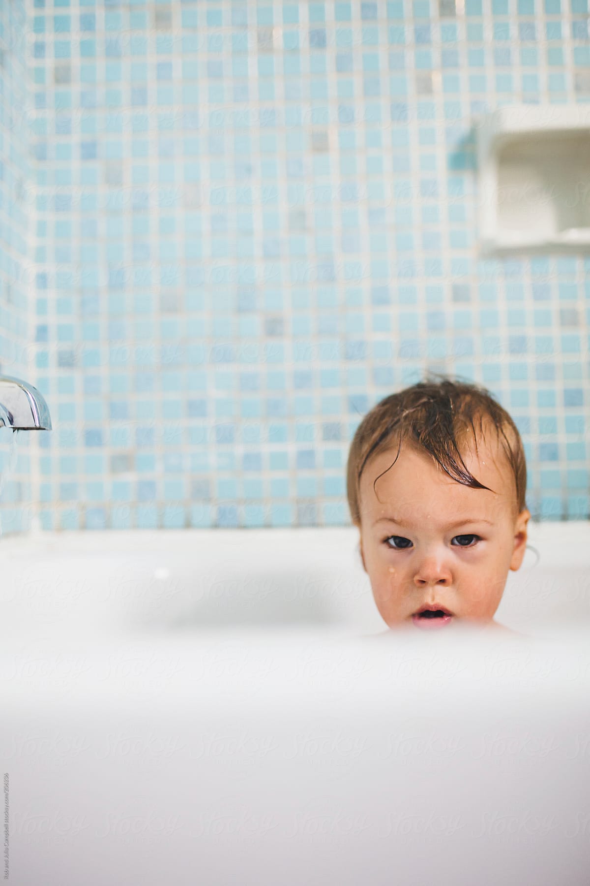 Cute baby boy girl scowling in bath tub