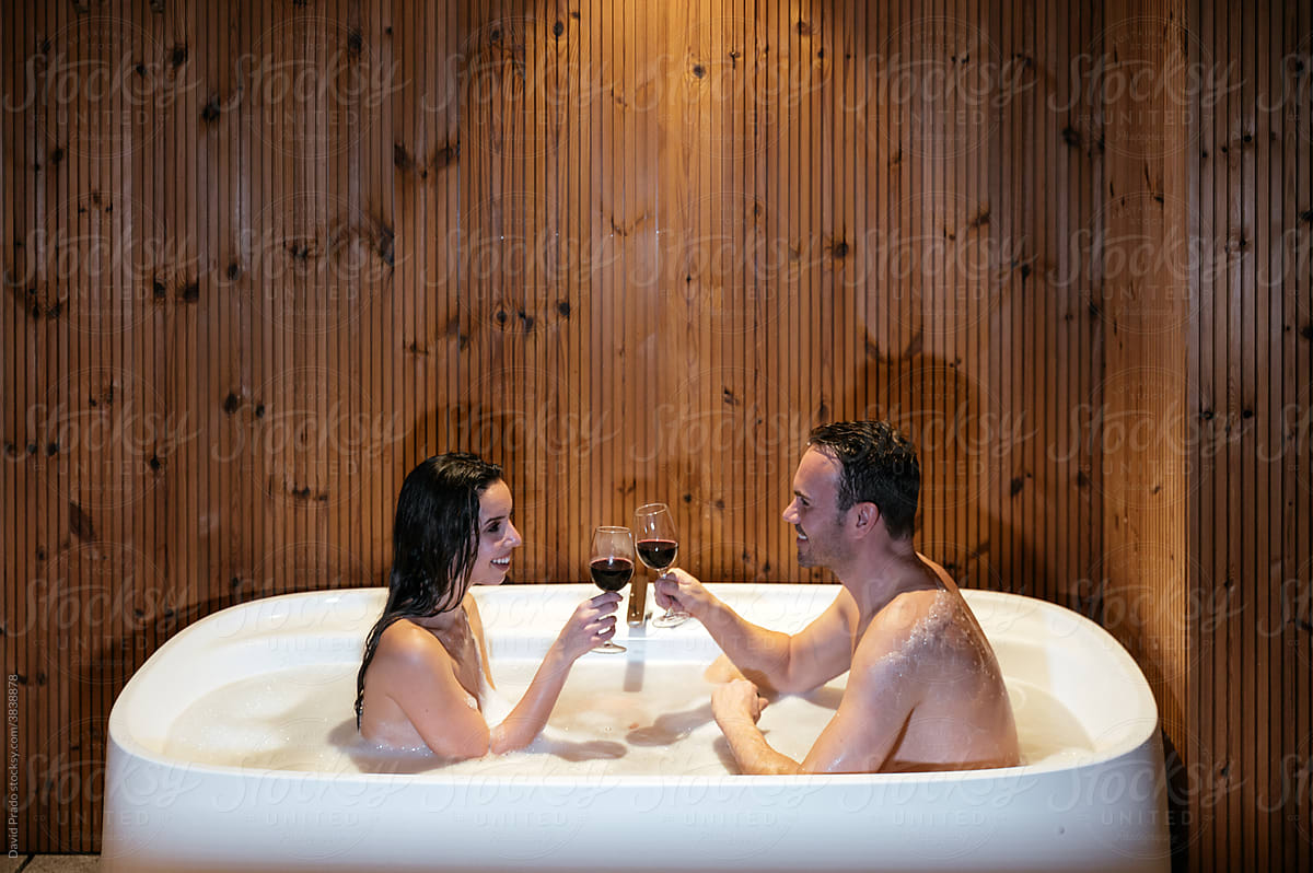 Loving couple with wine relaxing in bathtub