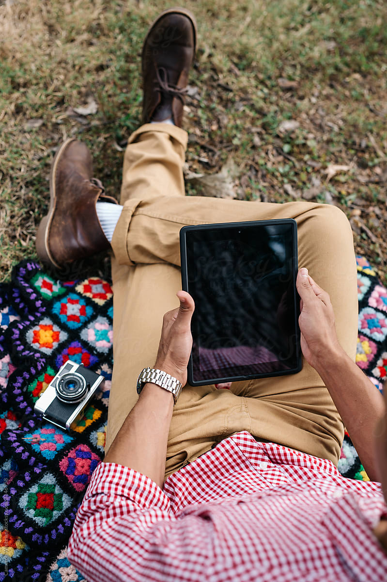 Man relaxing in the park using his digital tablet