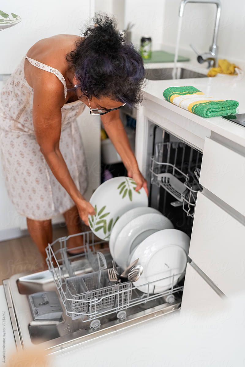 Woman putting dishes in dishwater.