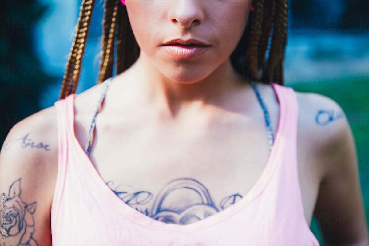 Young woman with tattoos and braids in a park