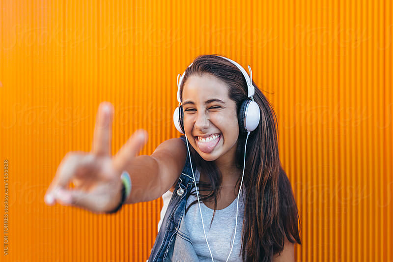 Happy Teen Girl with Headphones Doing the Victory Sign and Stick