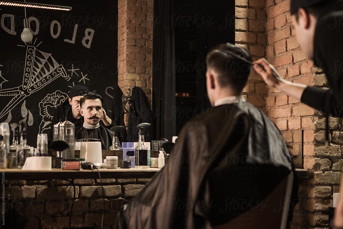 Young barber giving client a classic haircut in vintage barber shop