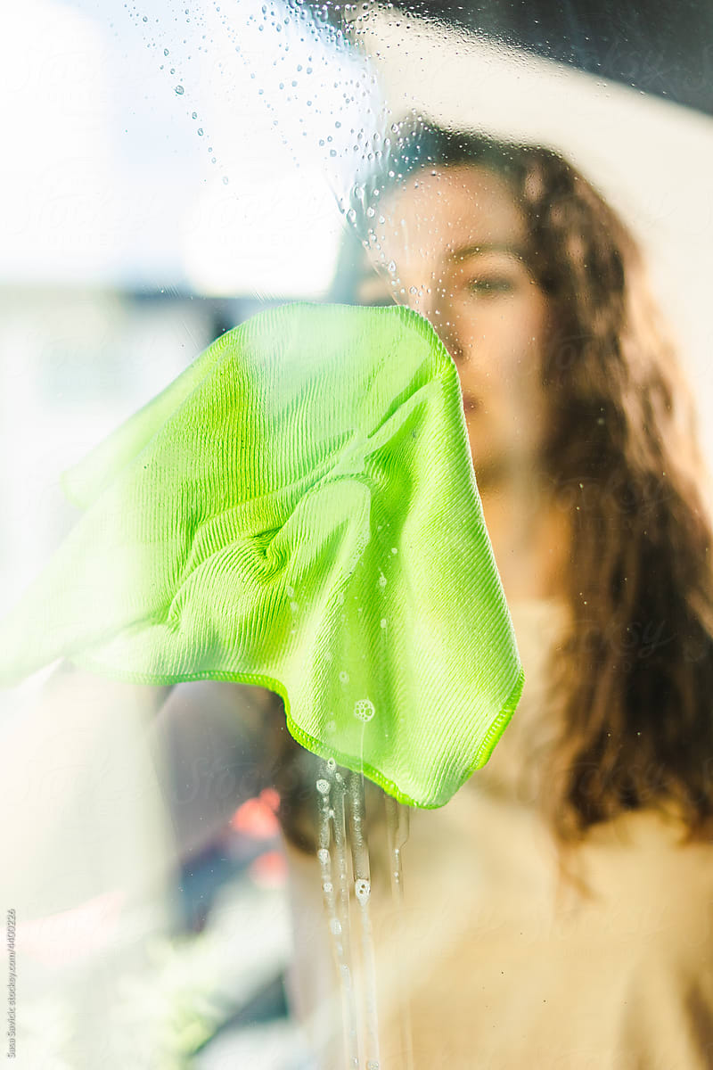 Woman cleaning window on sunny day