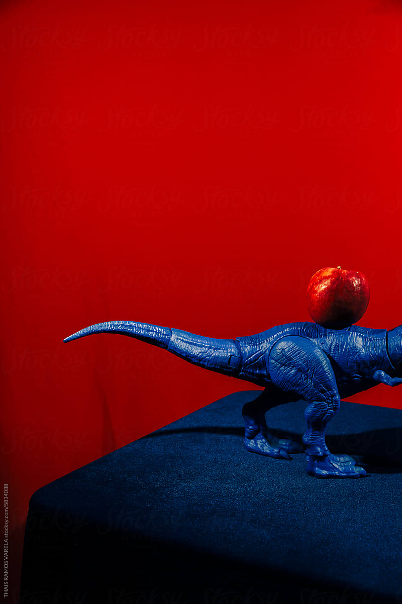 Blue Toy Dinosaur Positioned Next to a Red Apple