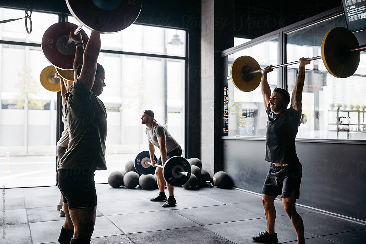 Men exercising with barbells in a crossfit box