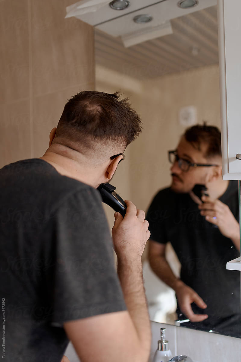 a nice man shaves with an electric razor