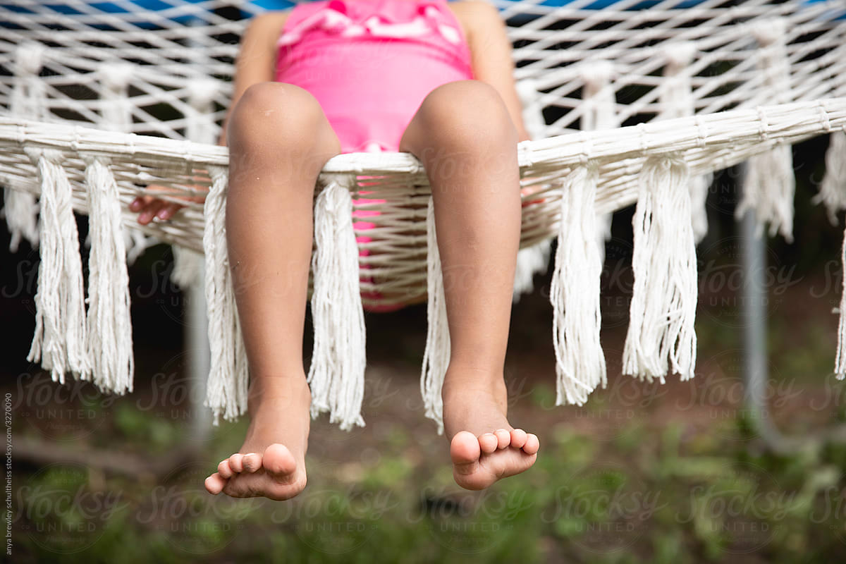 Closeup of a child\'s toes as she lounges in a hammock.