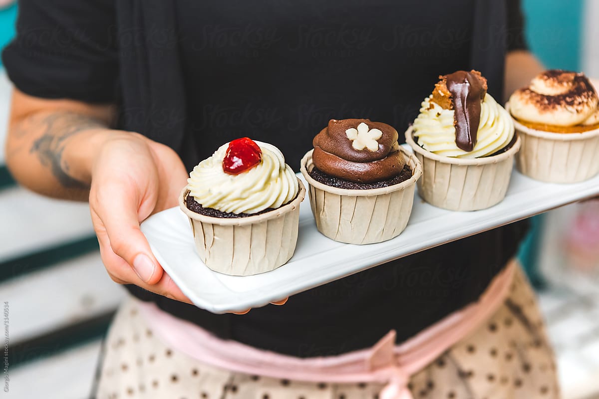Woman Holding a Tray with Four Different Cupcakes