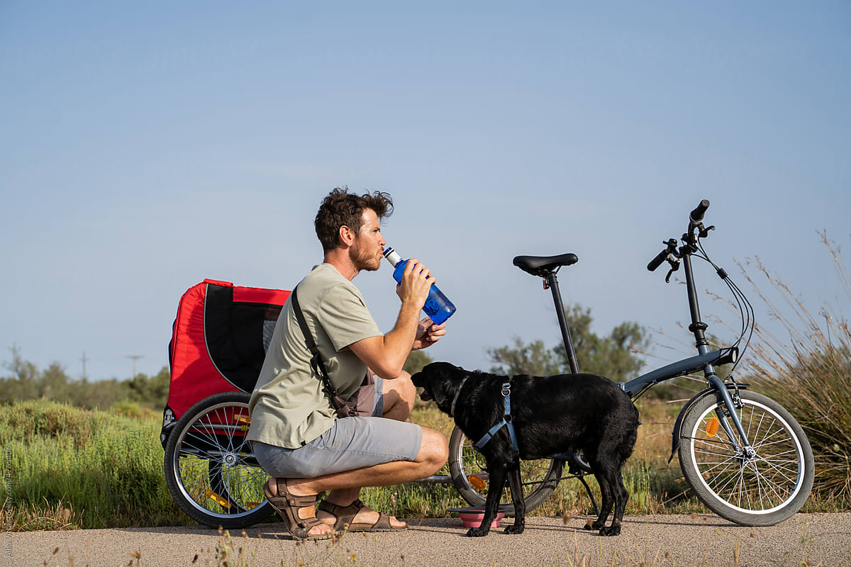 Man giving water do thirsty dog outdoors