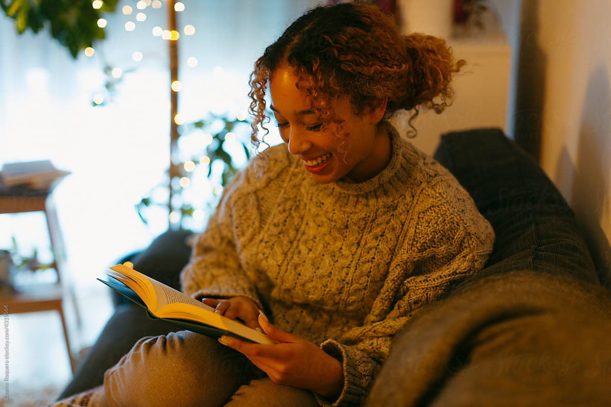 Young woman reading on the couch smiling