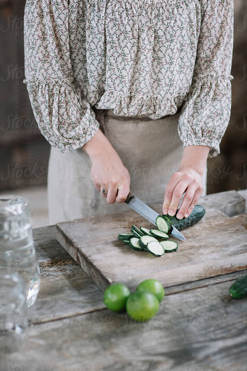 Crop Woman cutting cucumber for water