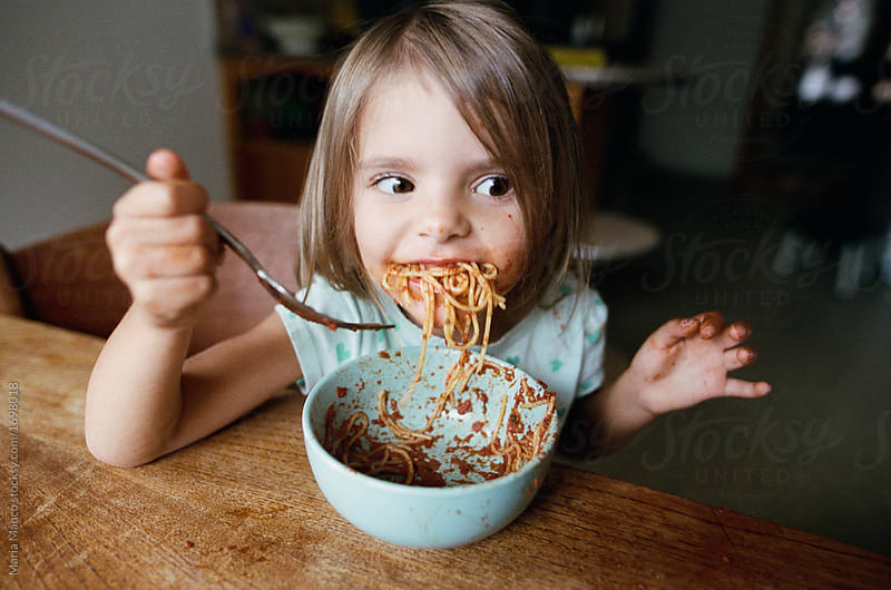 Kid making a mess and eating pasta