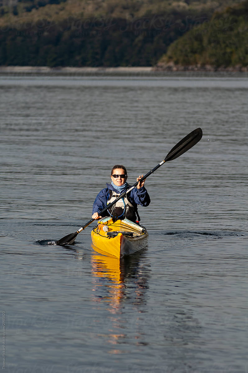 Woman paddling a kayak in Fiordland National Park, New Zealand.