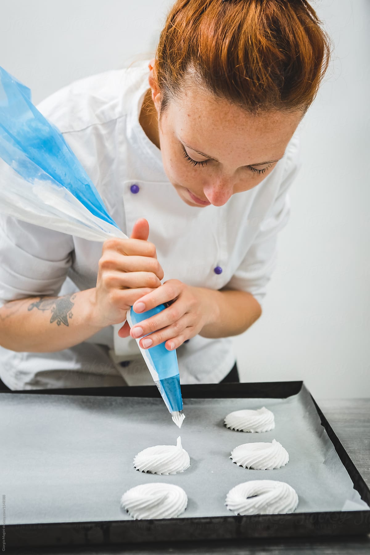 Pastry Chef with a Pastry Bag Preparing Meringues to Bake
