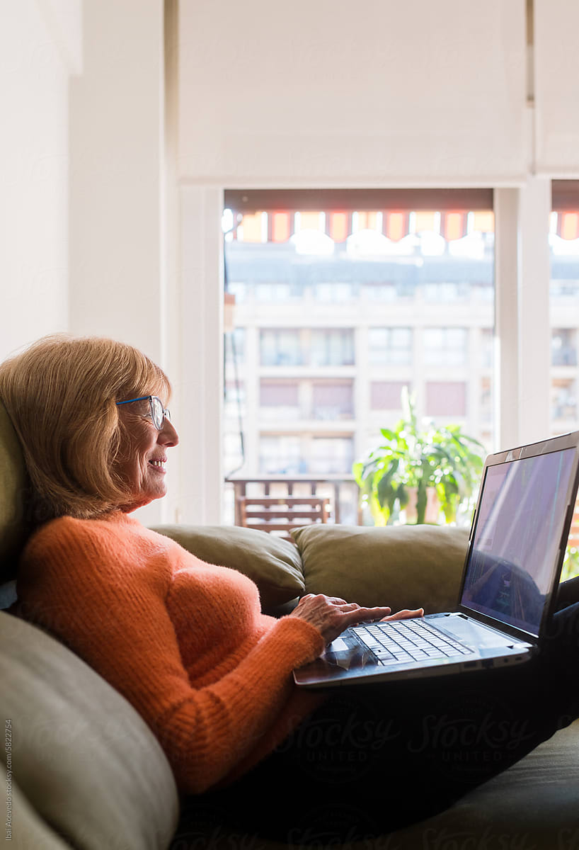 Relaxed senior woman with laptop on sofa