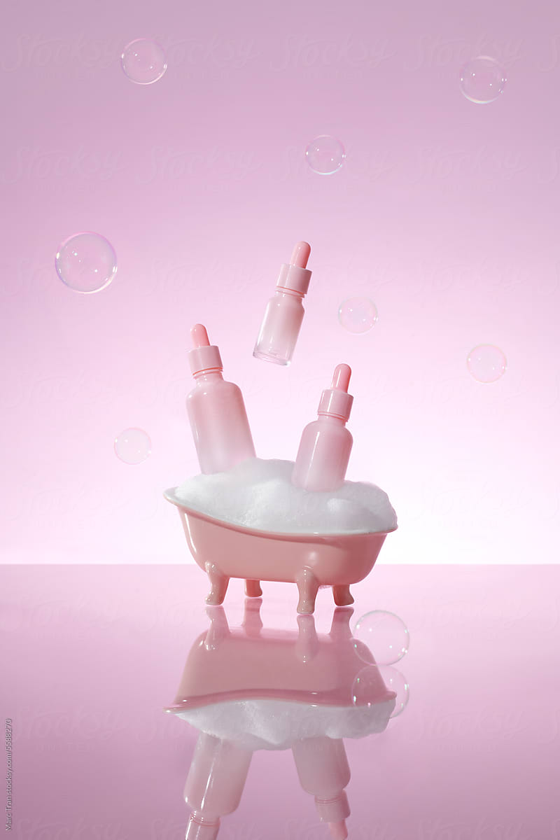 White bathtub with set cosmetics products on pink background
