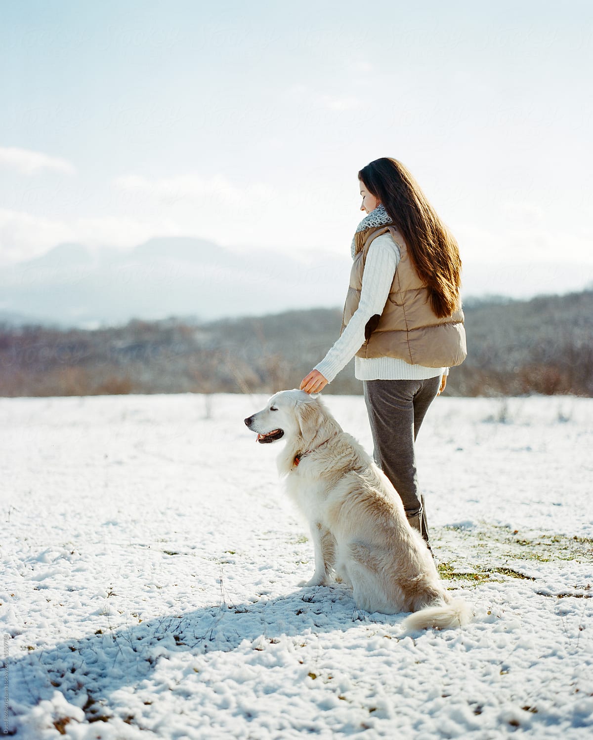 Woman stroking dog on snowy field