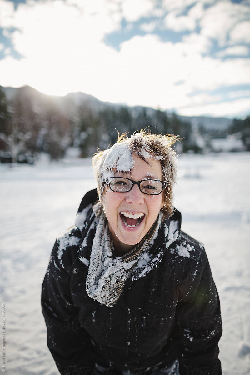 Happy mature woman covered in snow outside in winter (post snow fight)