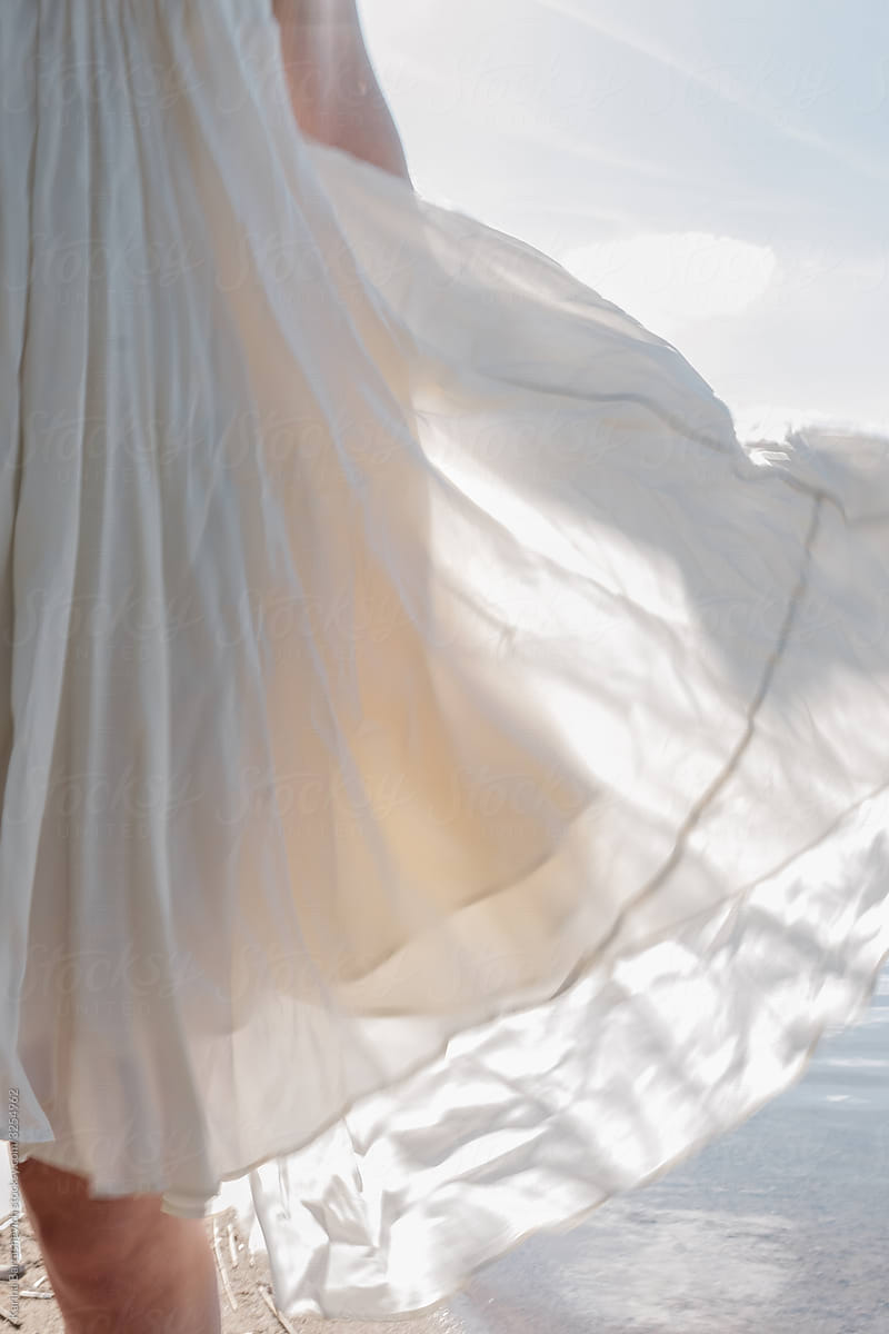 a photo of an airy flying dress on a girl while walking in nature, which flies in the wind